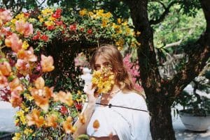 a woman in a white shirt holding a yellow and red flower